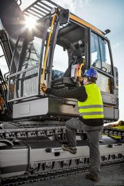 Erdbaumaschinenführer beim Aufsteigen auf Raupenbagger